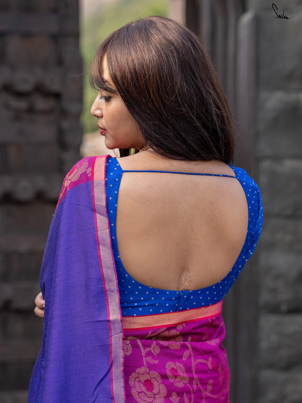 Woman wearing a blue and pink saree with a blurred background