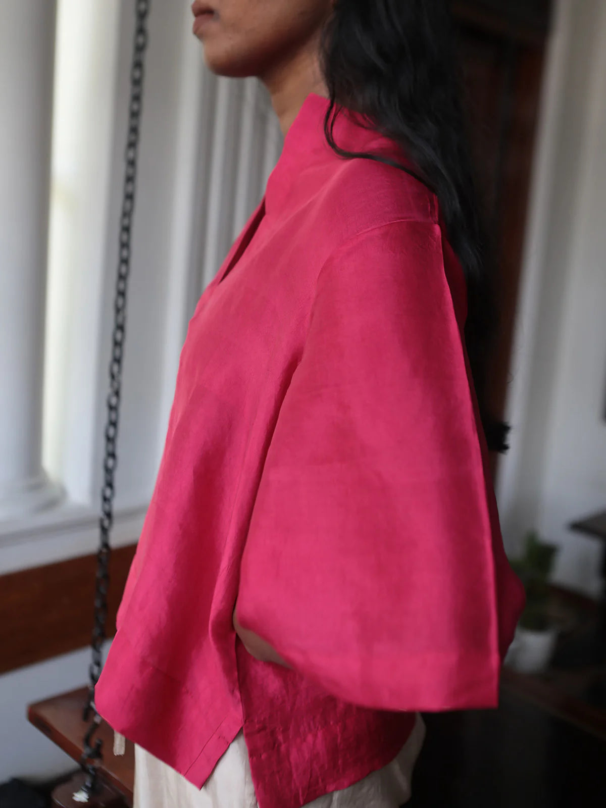 Person wearing a bright pink top indoors with a blurred background