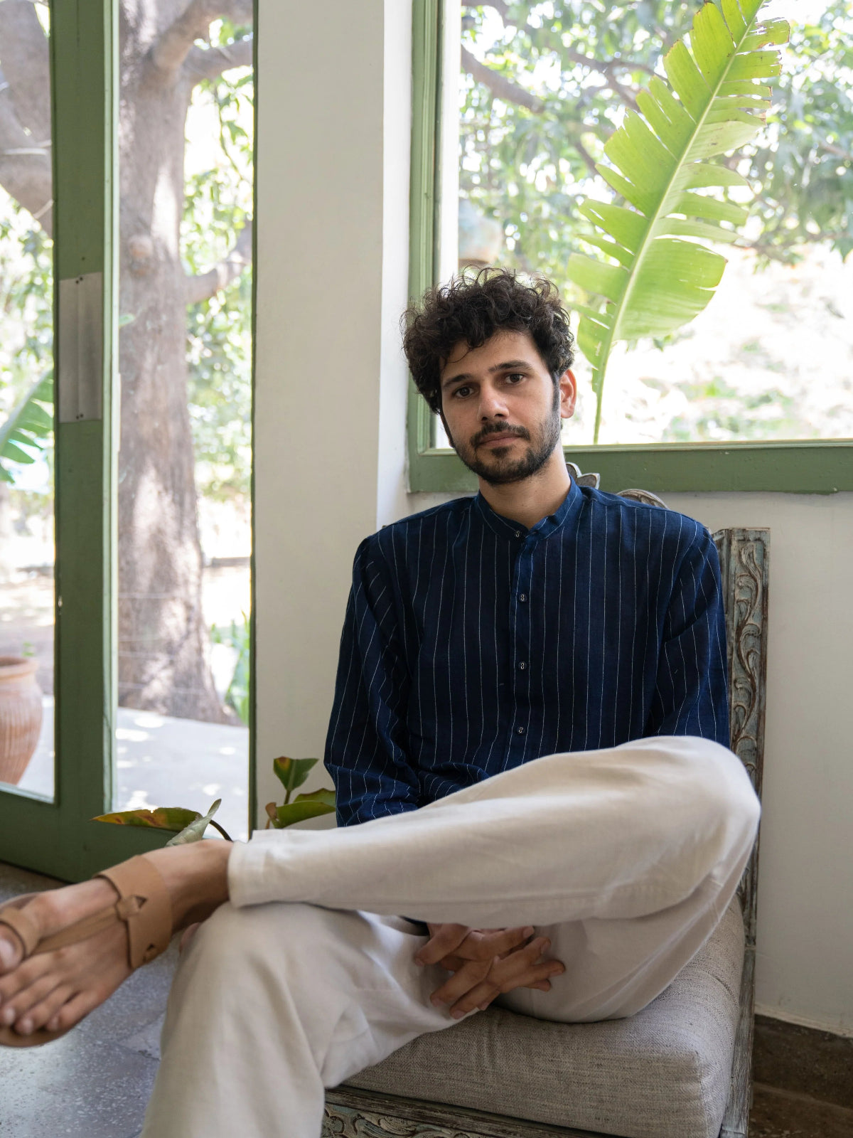 Man sitting on a chair by a window with plants in the background