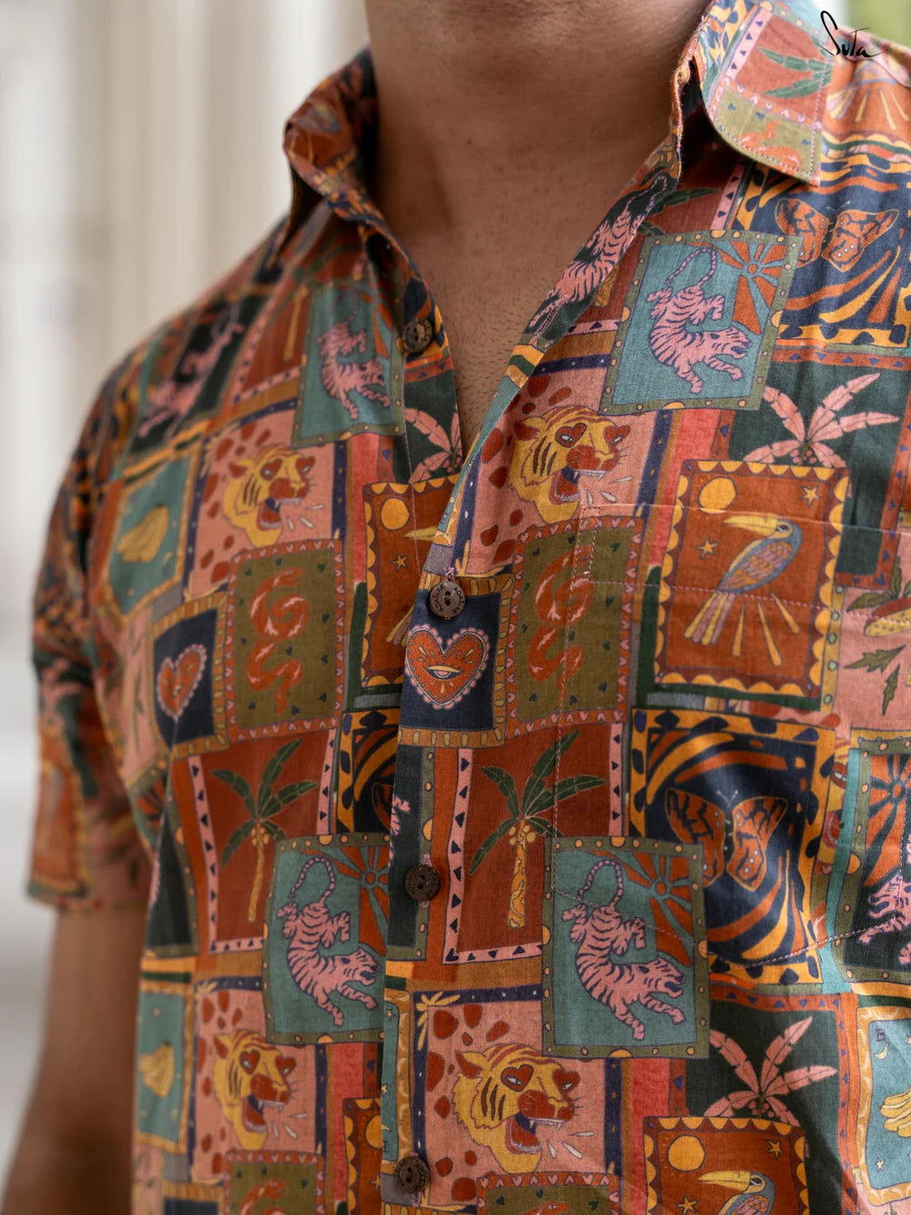 Close-up of a person wearing a colorful patterned shirt with various designs.