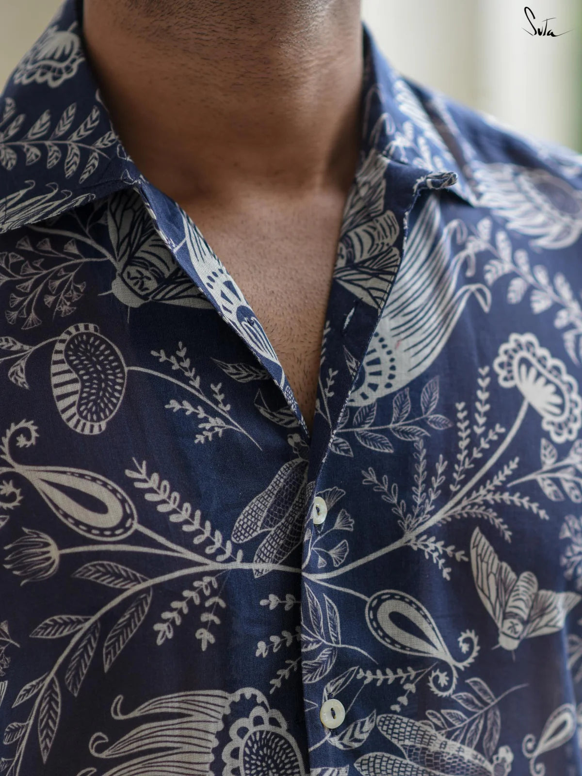 Close-up of a person wearing a blue patterned shirt with white designs.
