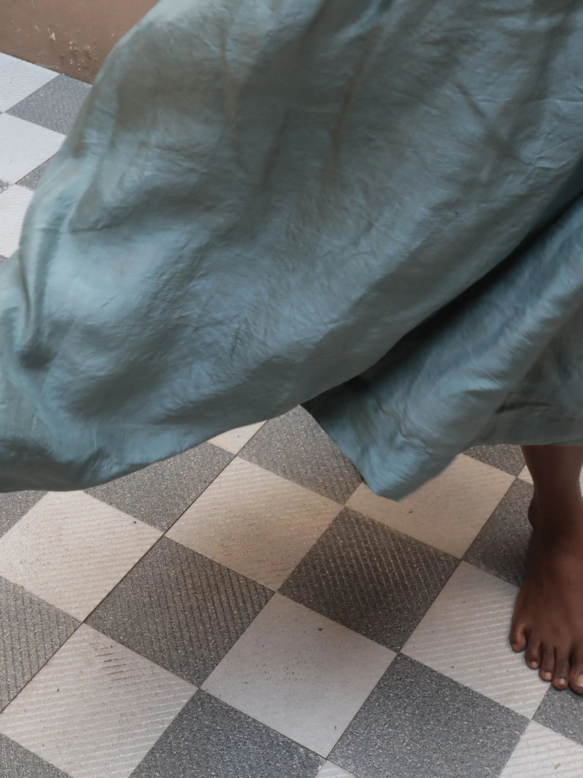 Blue silk dres fabric draped over a person on a checkered floor