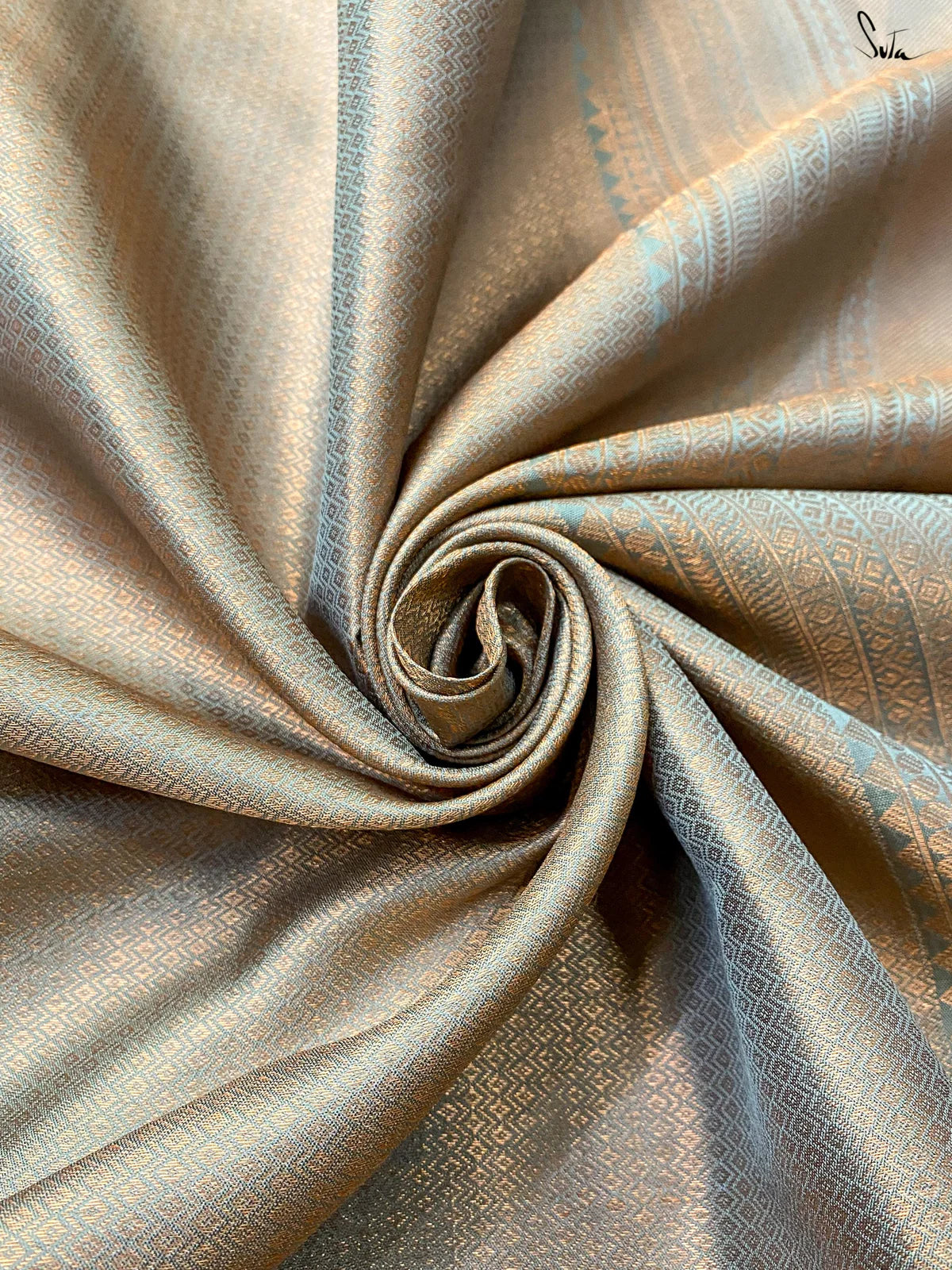 Rolled-up fabric with a subtle pattern on a gold background