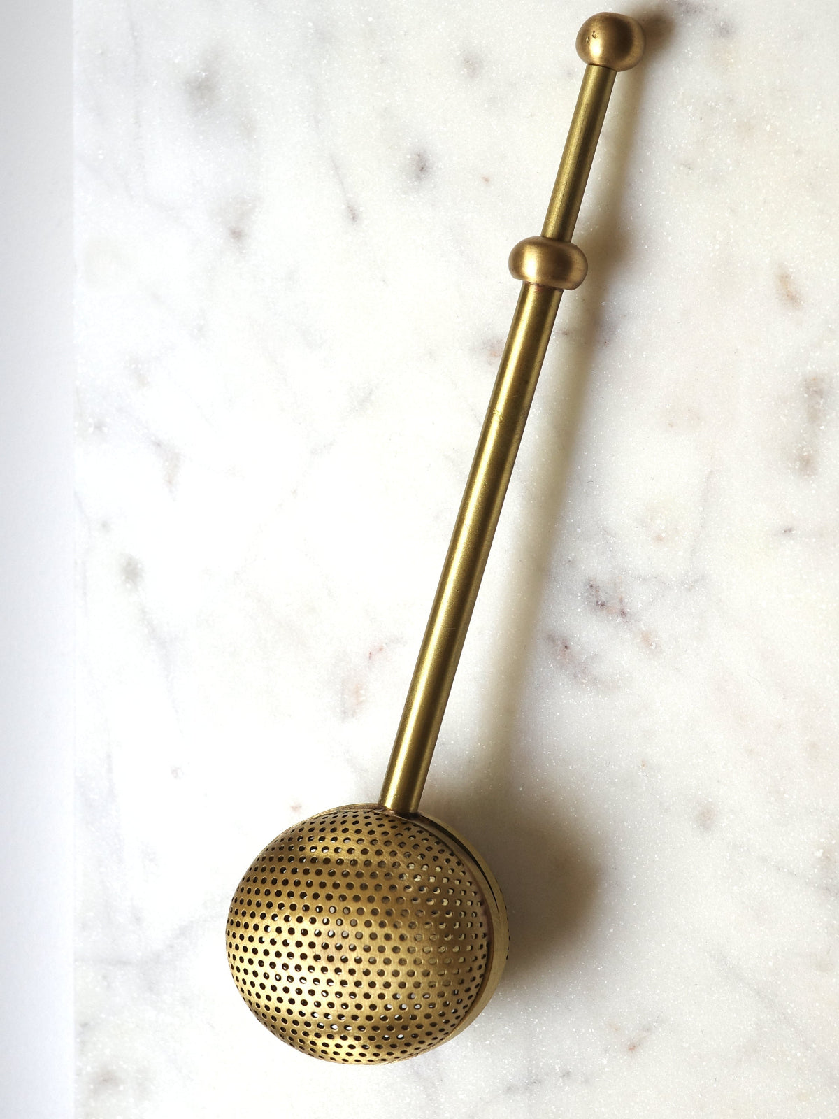 Gold mesh strainer on a marble surface