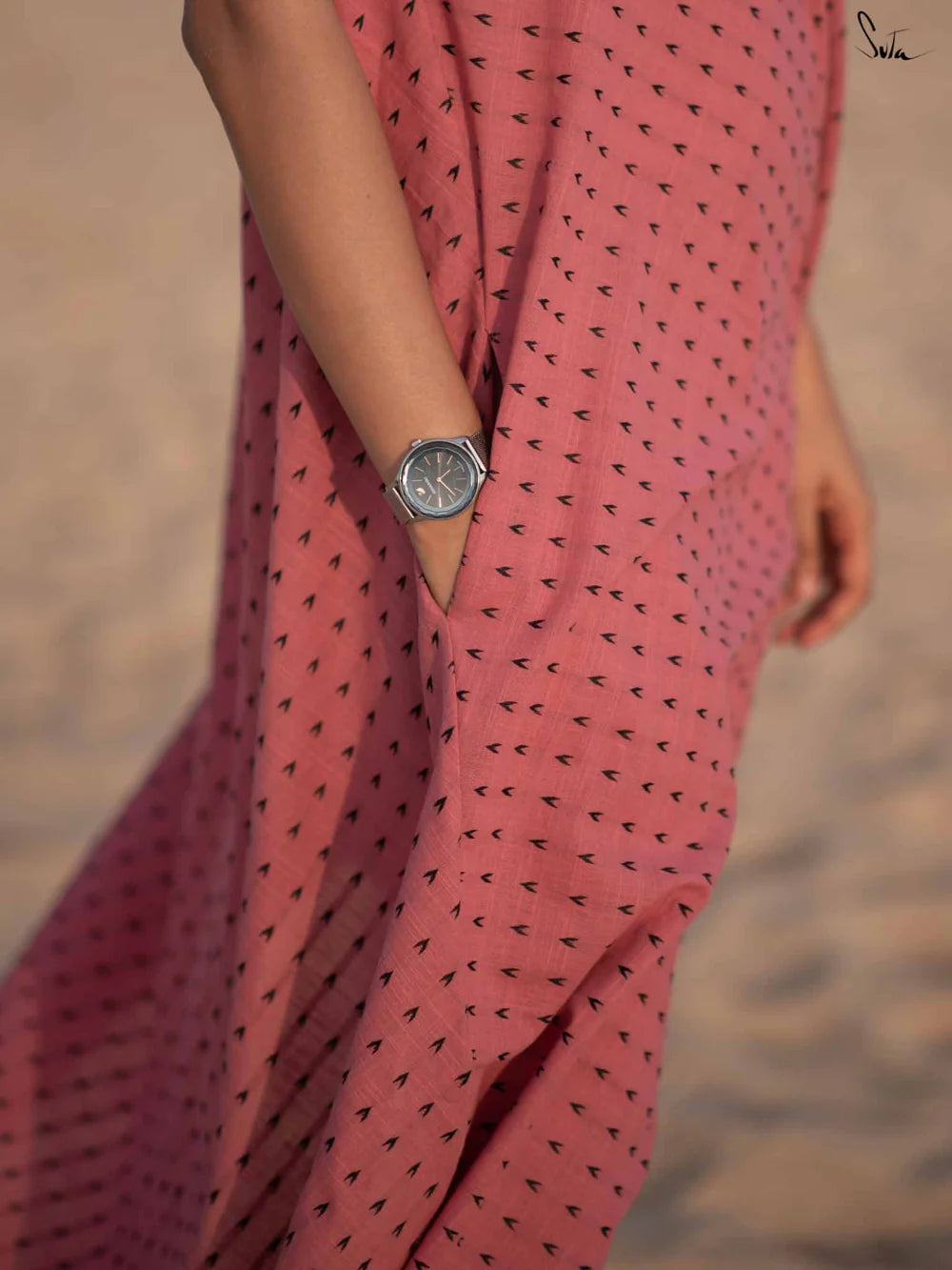 Person wearing a pink dress with black patterns on a blurred background
