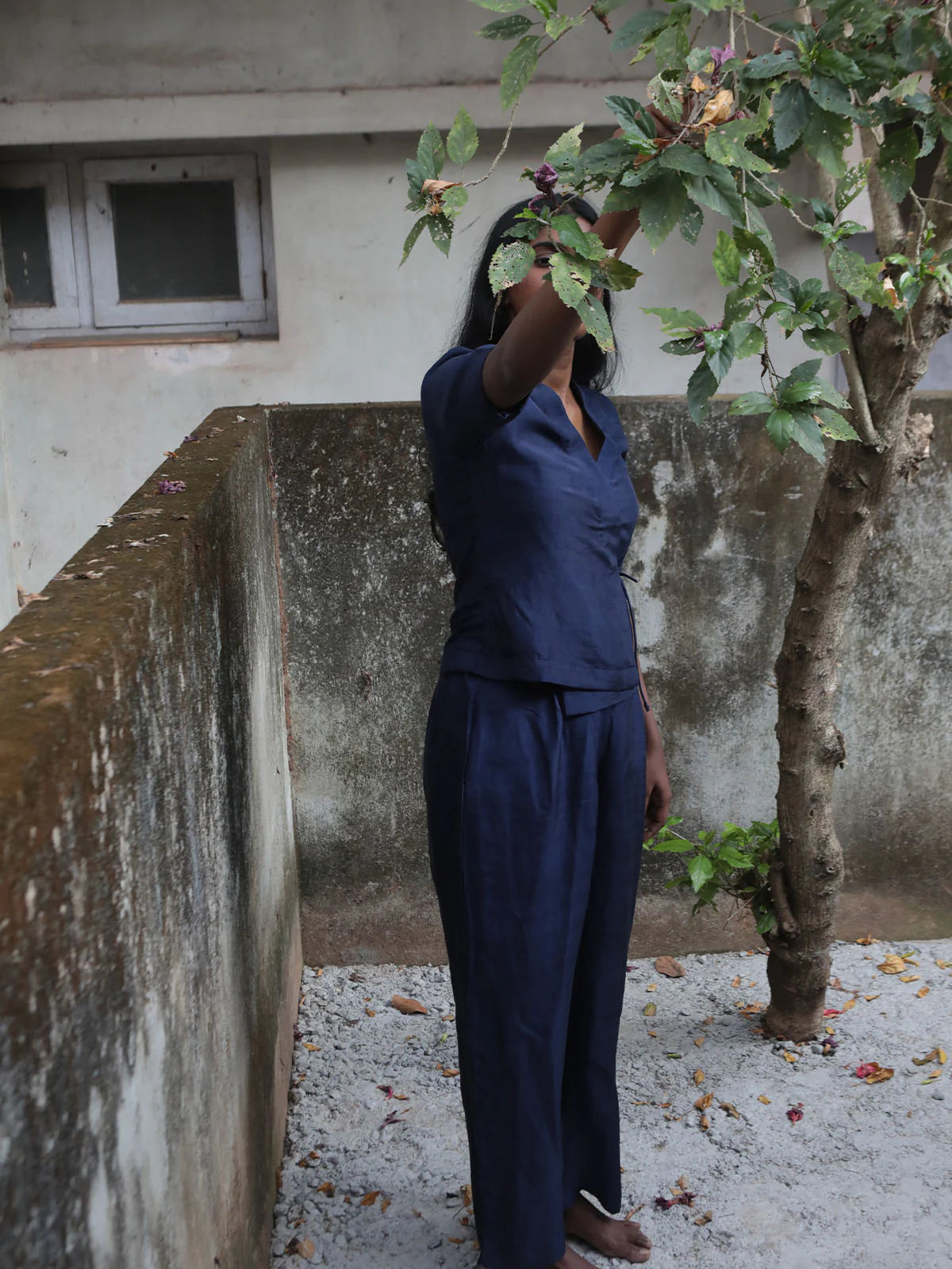 Woman wearing a navy blue shirt against a gray wall.