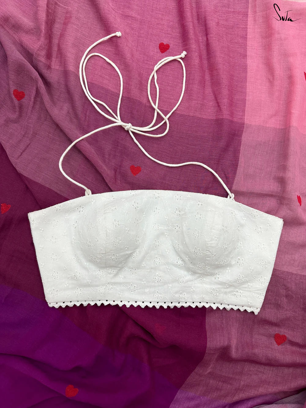 White blouse on a pink fabric background with red heart shapes.