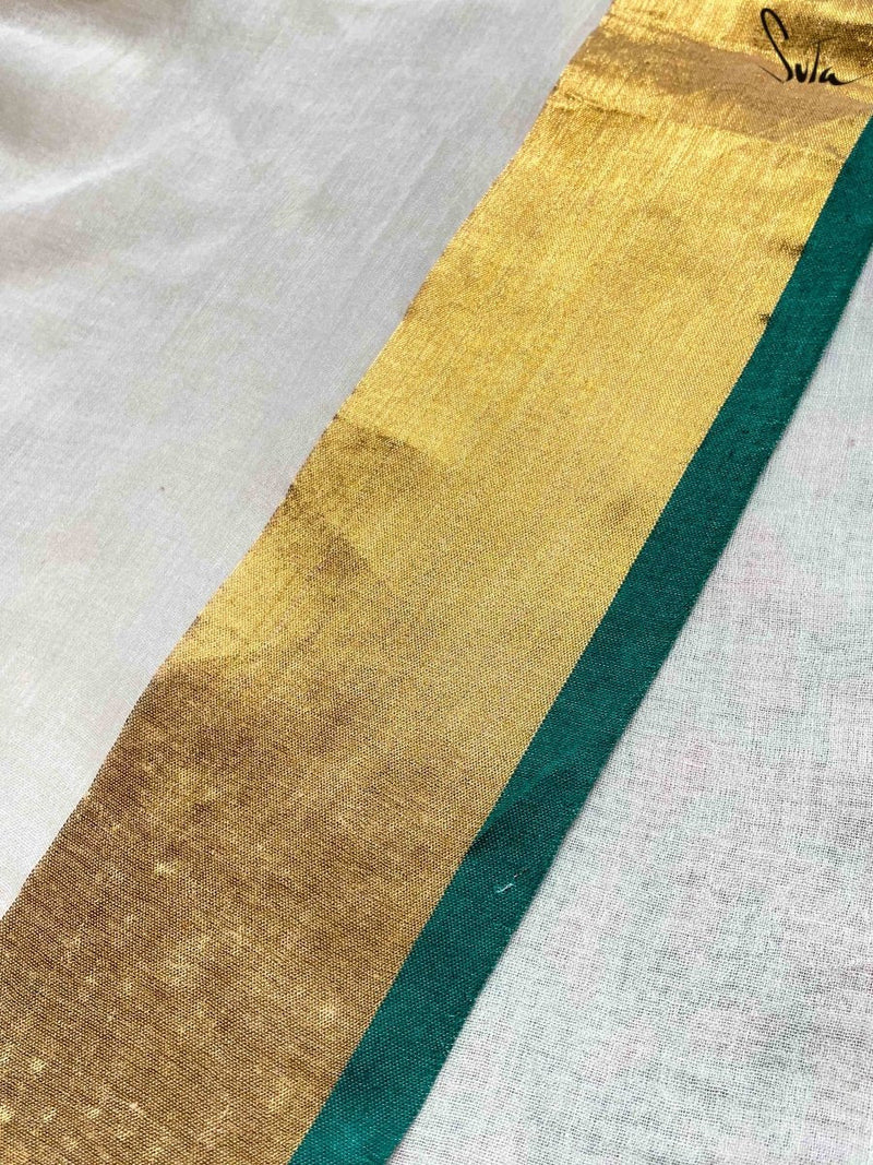 Close-up of a gold and green border fabric strip on a white saree