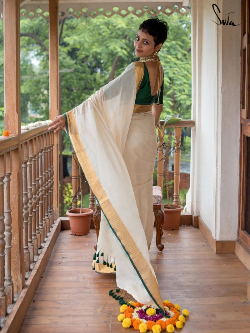 Woman in a traditional saree on a wooden balcony with greenery in the background