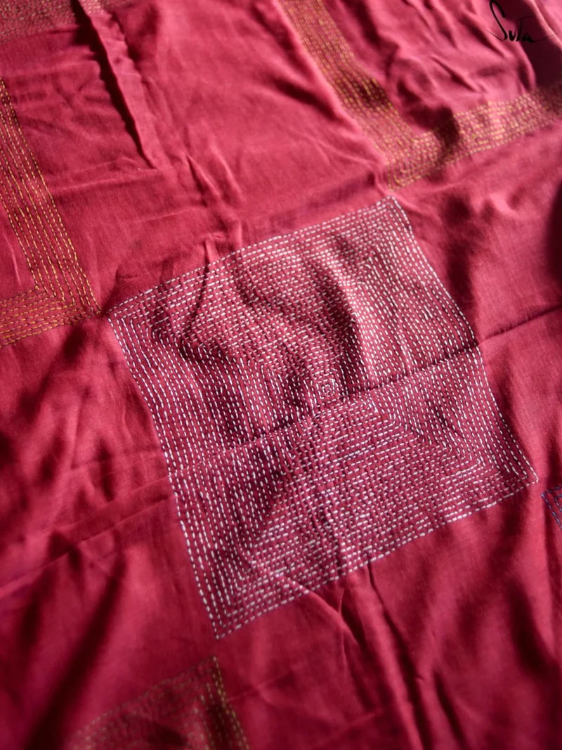 Close-up of a maroon fabric with a square katha embroidery patch