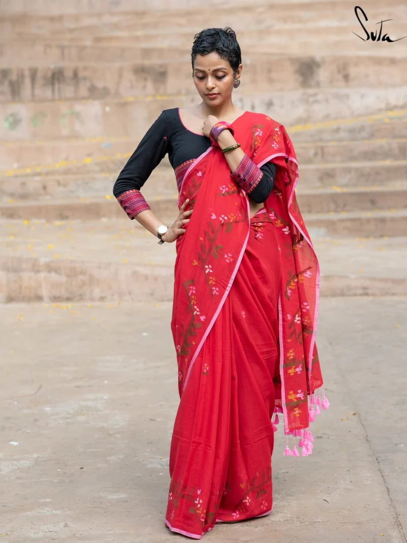 Woman wearing a red saree with floral patterns on a stone staircase background