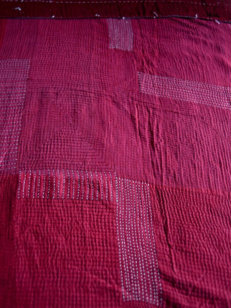 Close-up of a textured red fabric with a checkered katha pattern