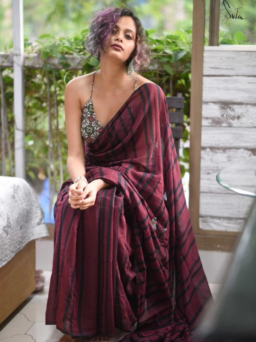Woman wearing a maroon saree with a green blouse in an outdoor setting