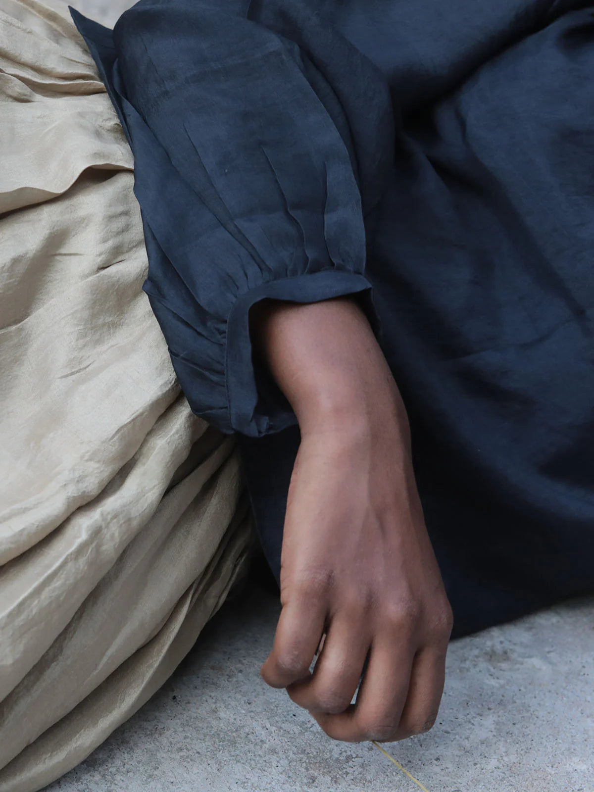Person wearing a black top with a beige skirt and gray floor in the background