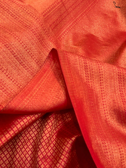 Close-up of red fabric with intricate patterns made of gold zari