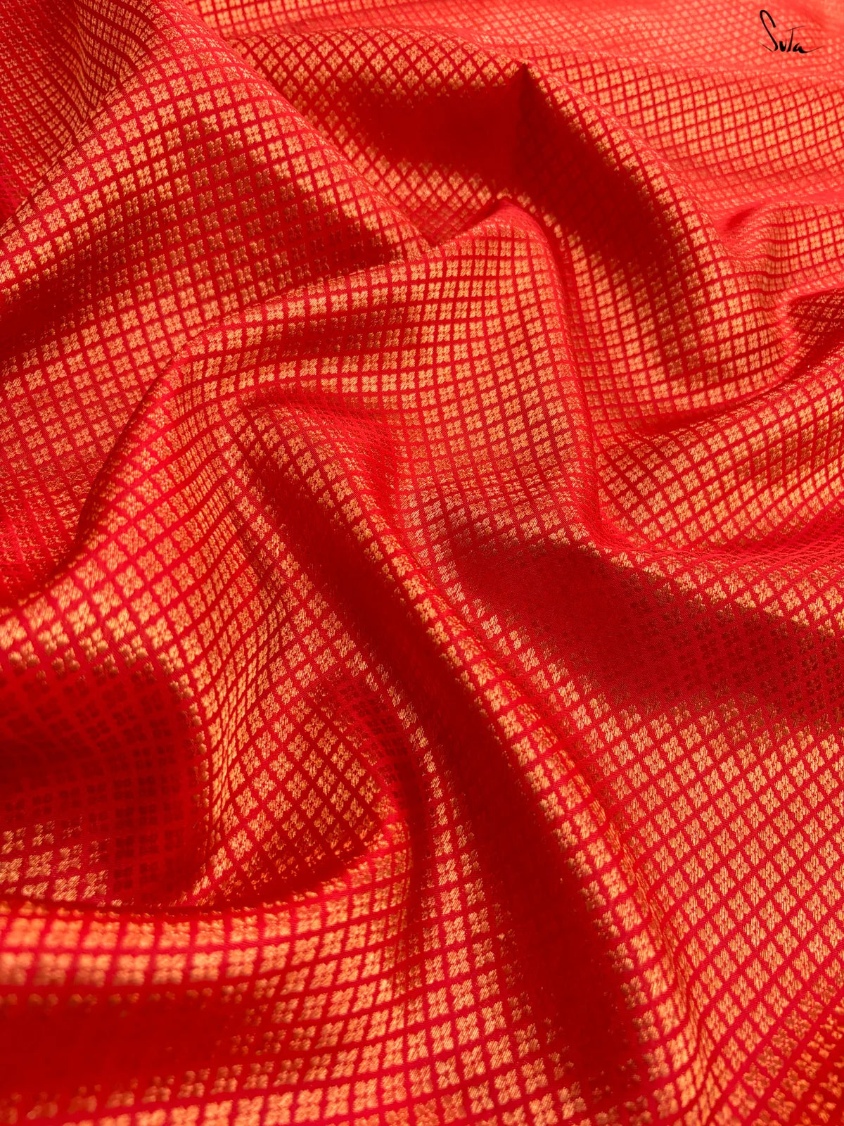 Close-up of red fabric with a subtle gold pattern