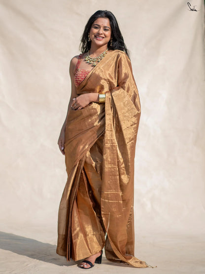 Woman wearing a pre draped gold chanderi saree with a plain background