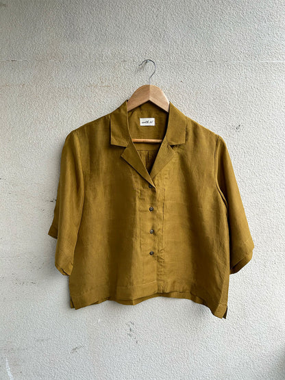 Yellow shirt on a hanger against a light gray wall