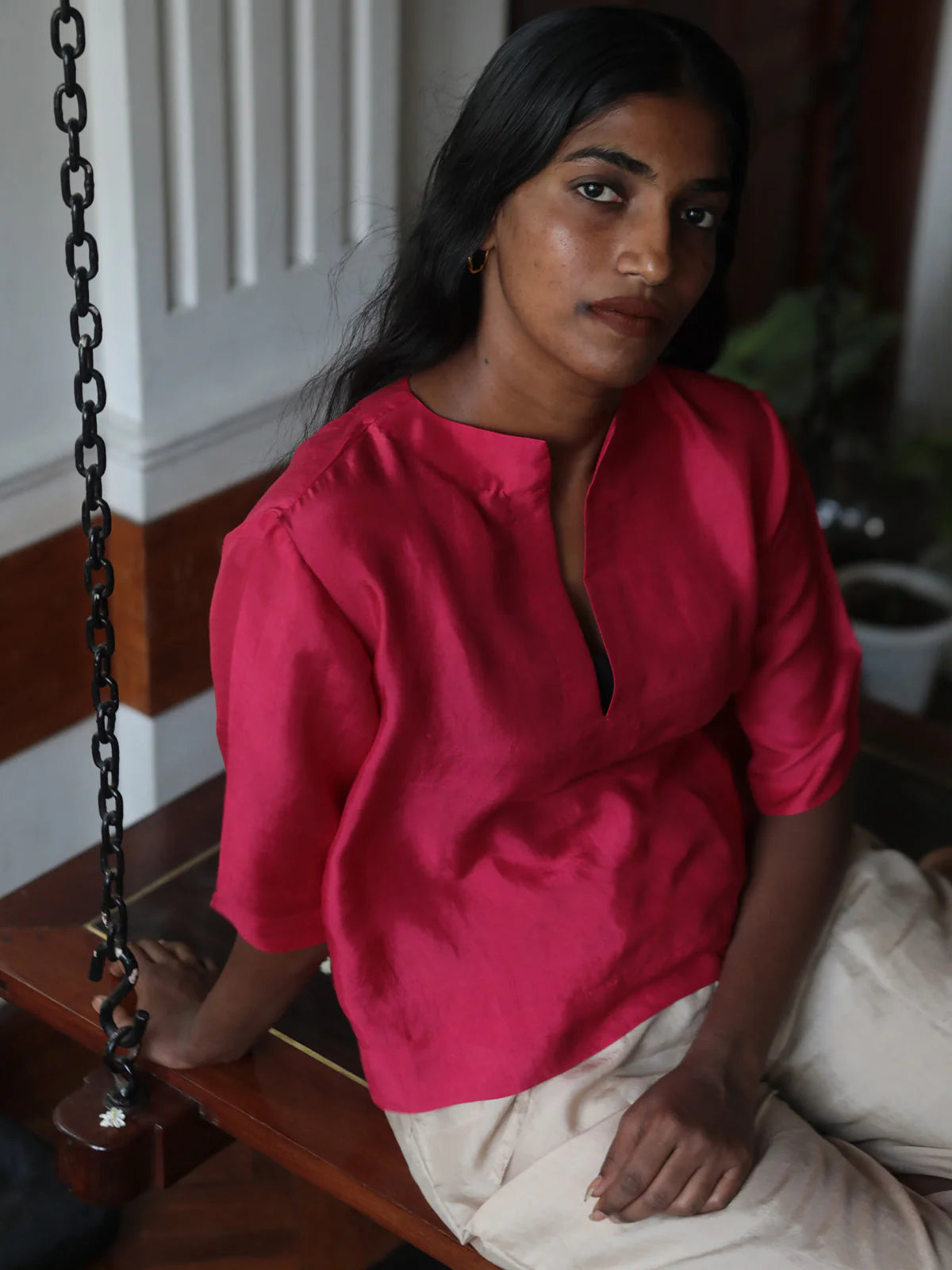 Woman in a pink top sitting on a wooden bench indoors