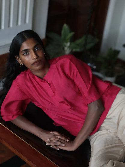 Woman in a pink top sitting on a wooden surface with a blurred background