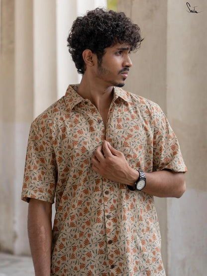 Man wearing a beige floral patterned shirt standing outdoors with columns in the background