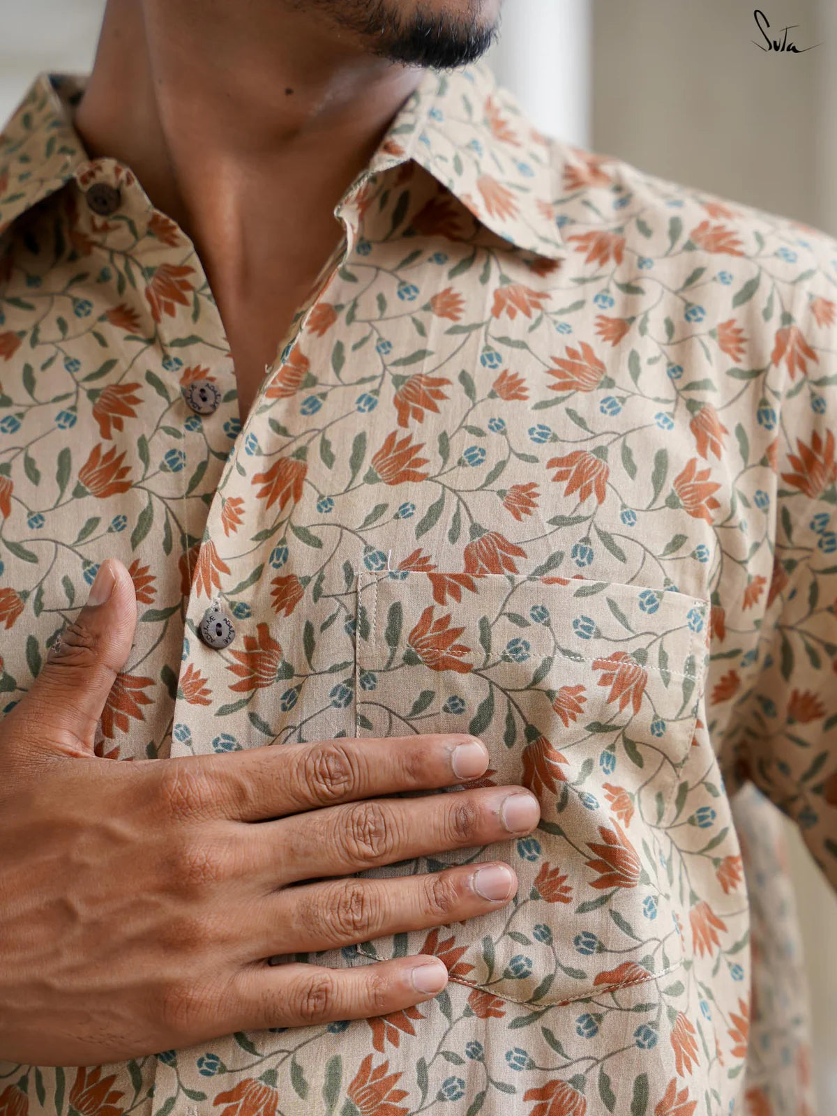 Person wearing a floral patterned shirt with a blurred background