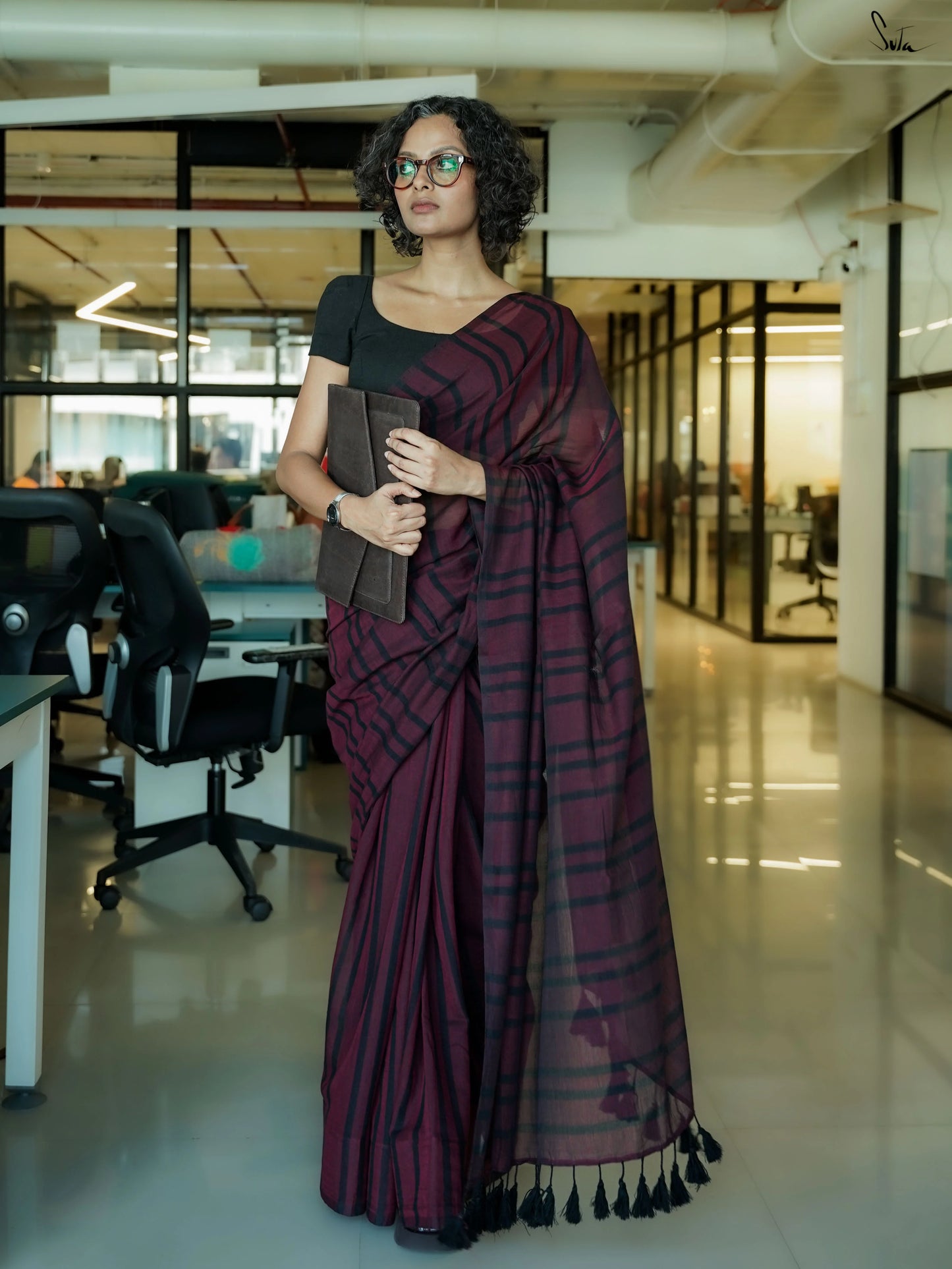 Woman in a maroon saree standing in an office setting