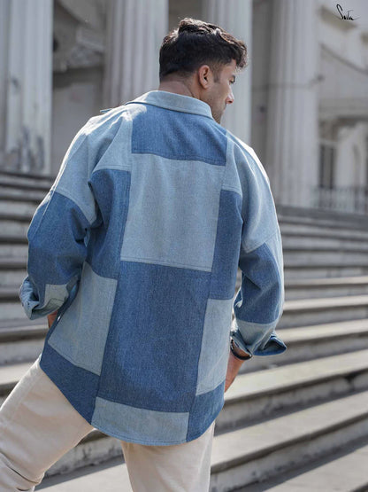 Man wearing a blue patchwork denim shirt standing on steps outdoors