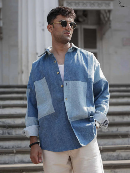 Man wearing a blue patchwork denim shirt standing on steps outdoors