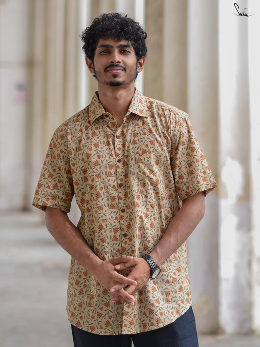 Man wearing a beige floral patterned shirt standing outdoors with columns in the background