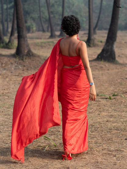 Woman in a red saree walking away in a forested area