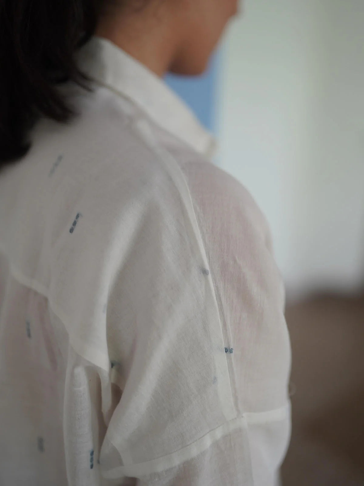 White shirt with small blue patterns worn by a person, blurred background