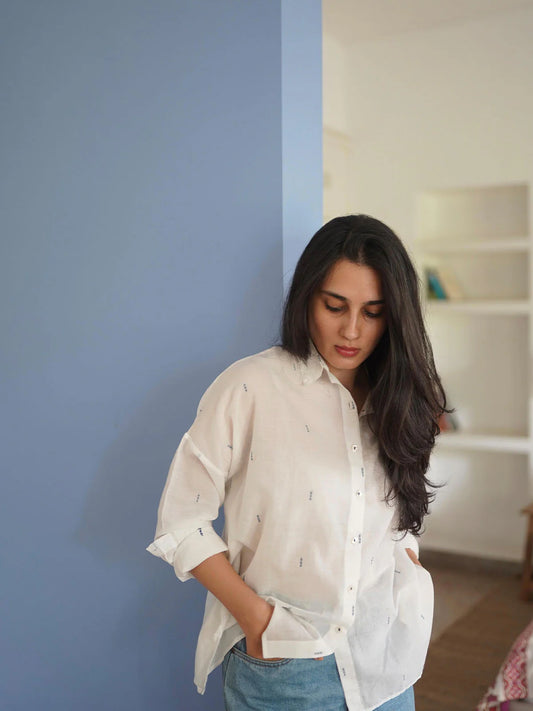 Woman wearing a white-colored shirt against a blue wall