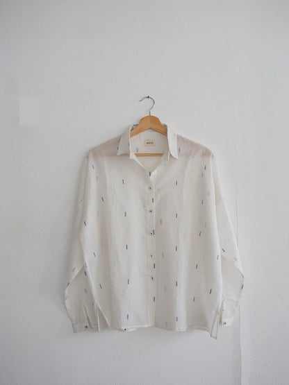 White shirt with subtle blue patterns on a wooden hanger against a white background