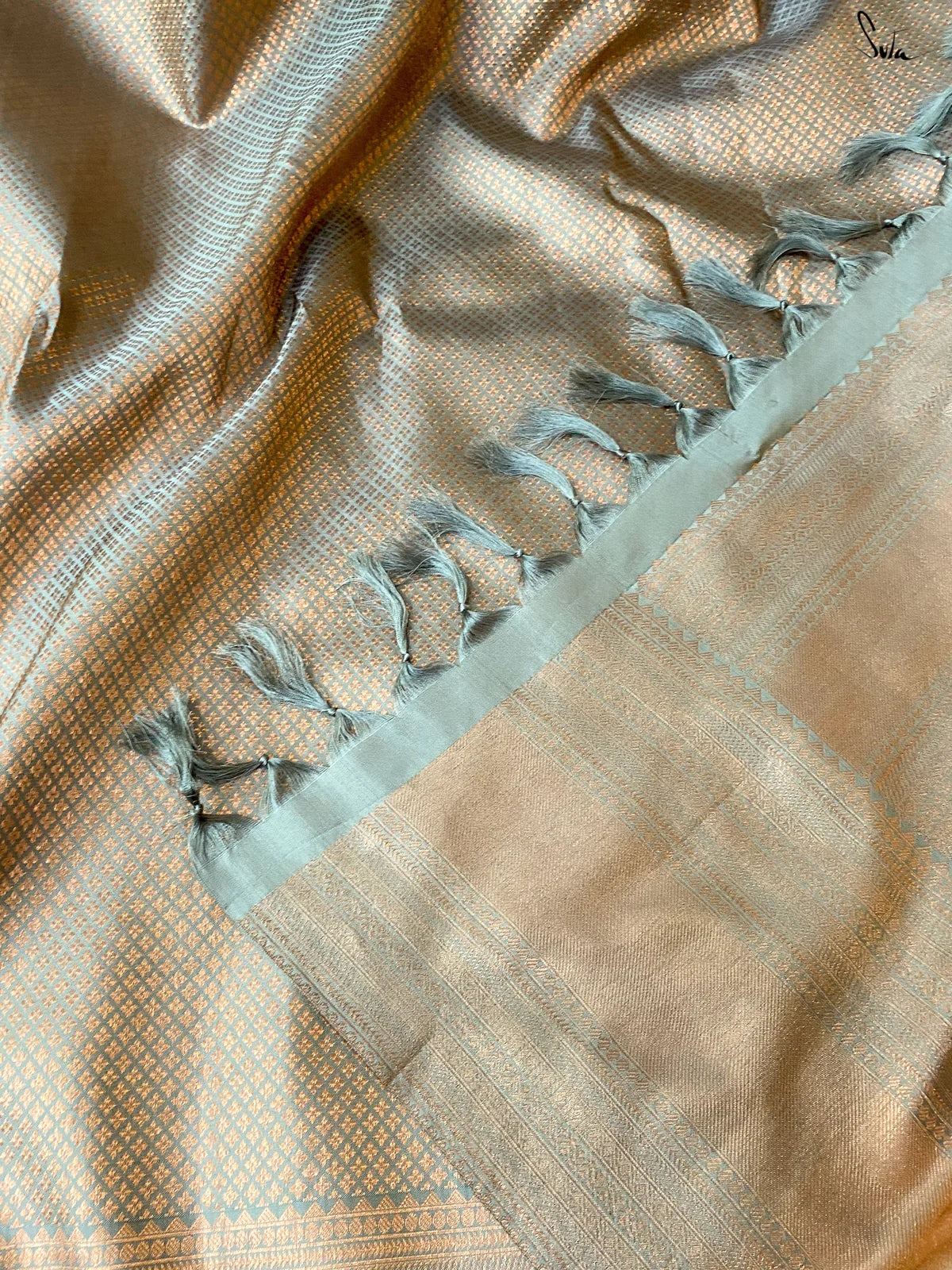 Close-up of a gold saree fabric with decorative blue tassels