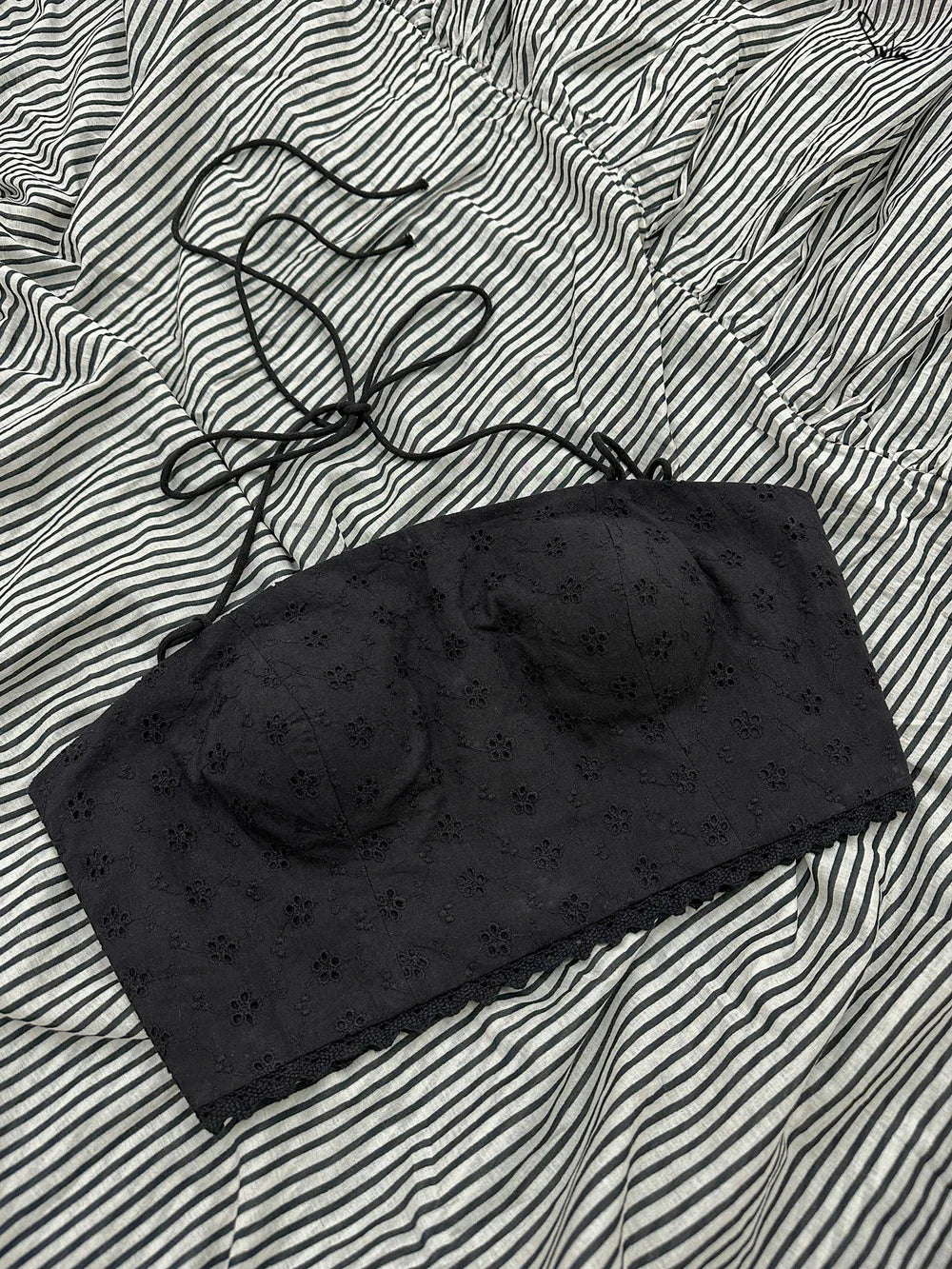 Black blouse with eyelet patterns on a striped fabric background