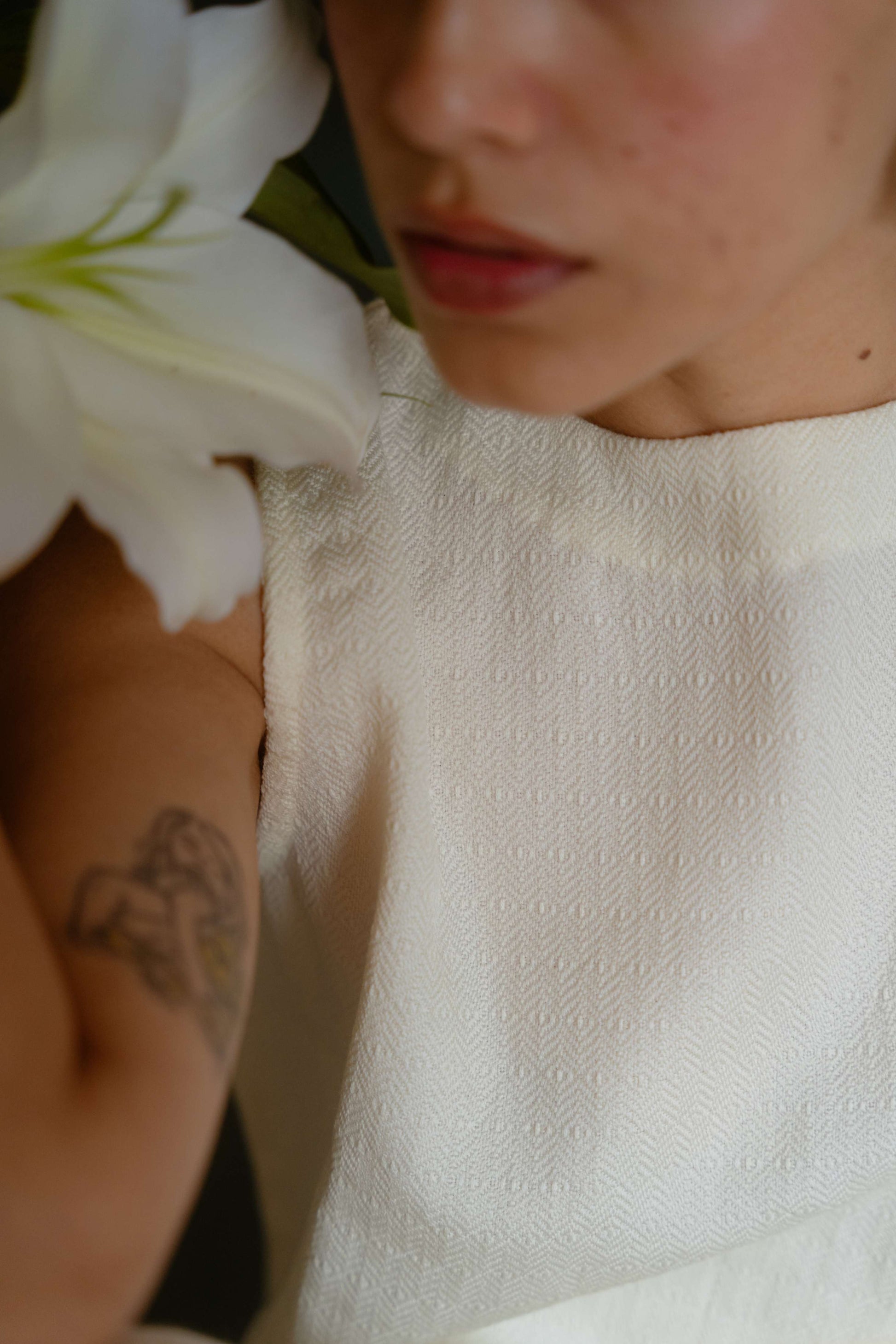 Person wearing a textured white garment with a close-up of a white flower.