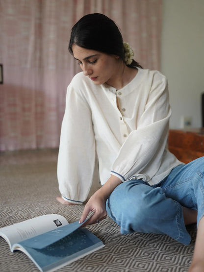 Woman reading a book on the floor wearing a beige shirt with a blurred background