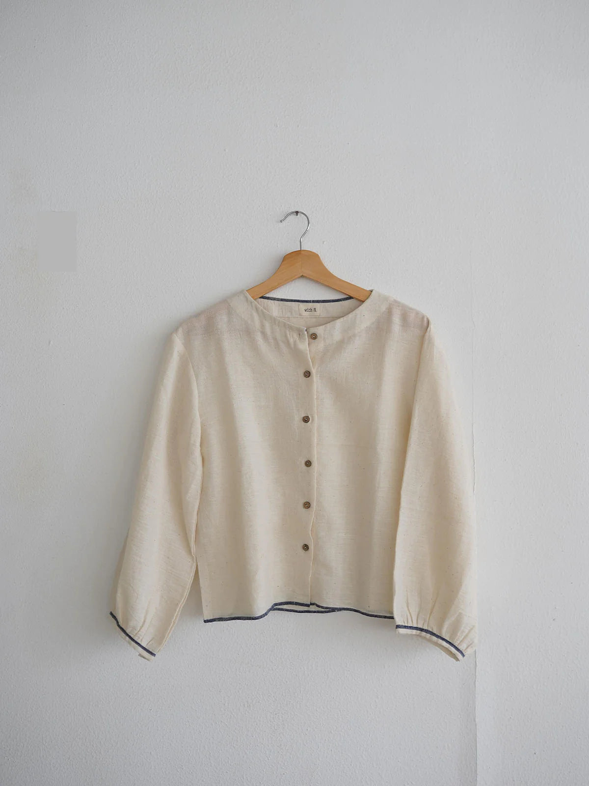 Beige blouse on a hanger against a plain background