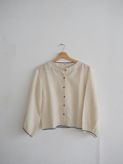 Beige blouse on a hanger against a plain background