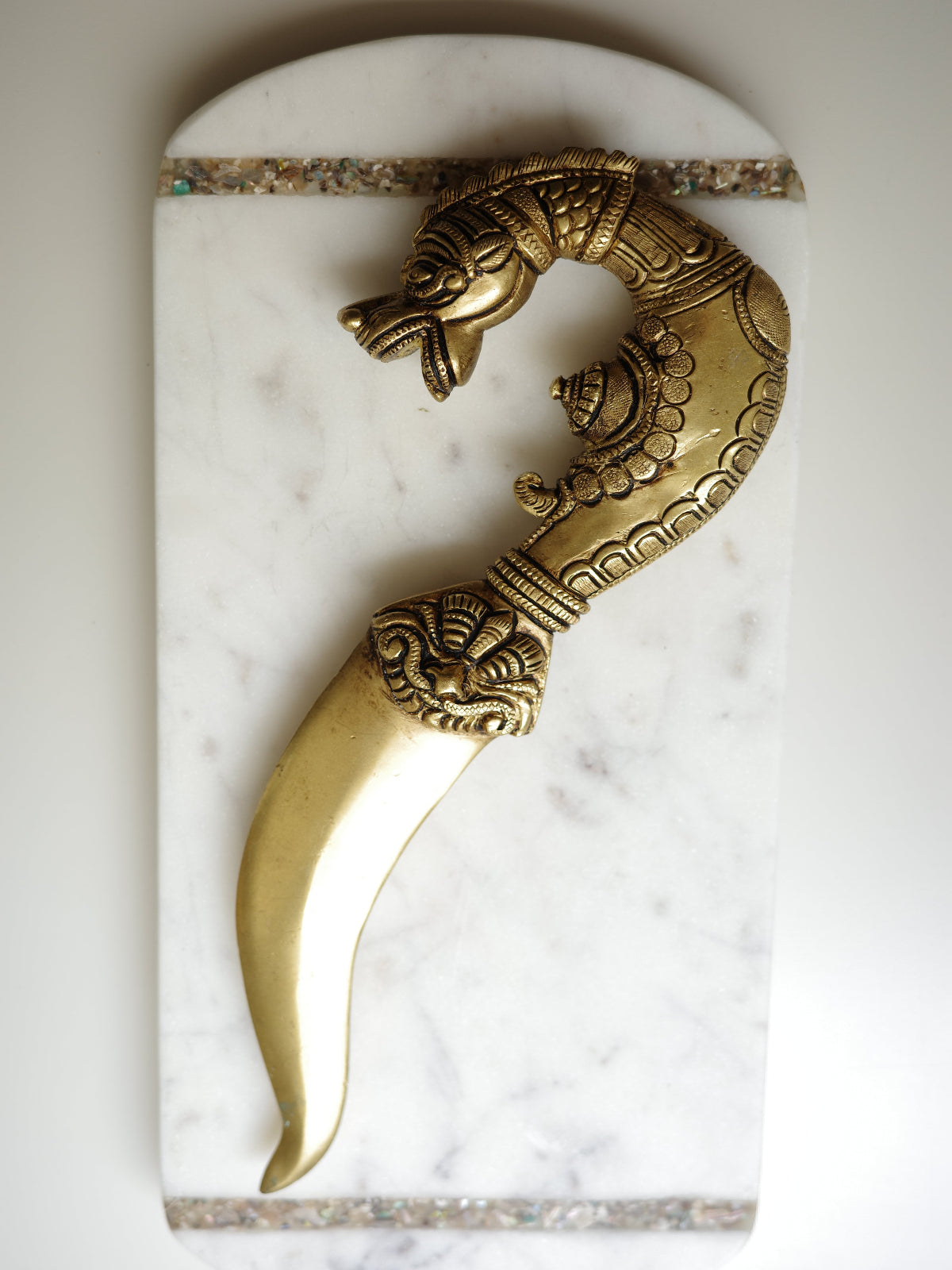 Decorative brass wall hook on a marble surface