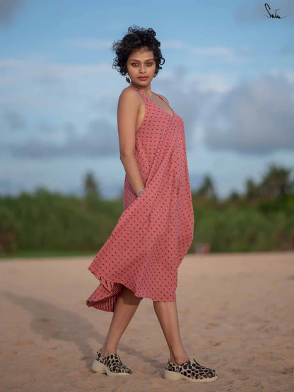 Woman in a pink dress standing on a beach with a blurred natural background