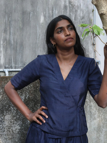 Woman wearing a navy blue shirt against a gray wall.