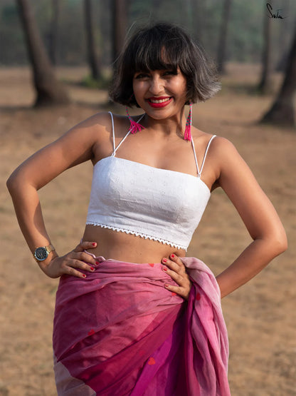 Woman in a white blouse and pink saree standing outdoors with trees in the background