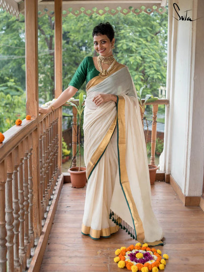 Woman in a white saree with gold border on a balcony