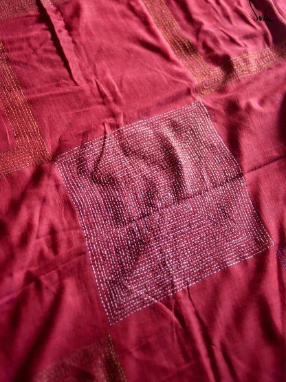 Close-up of a maroon fabric with a square katha embroidery patch