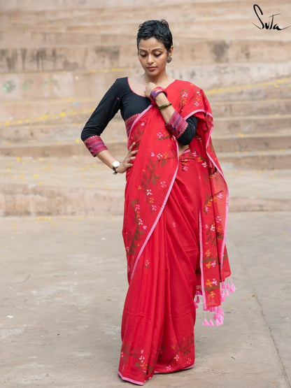Woman wearing a red saree with floral patterns on a stone staircase background