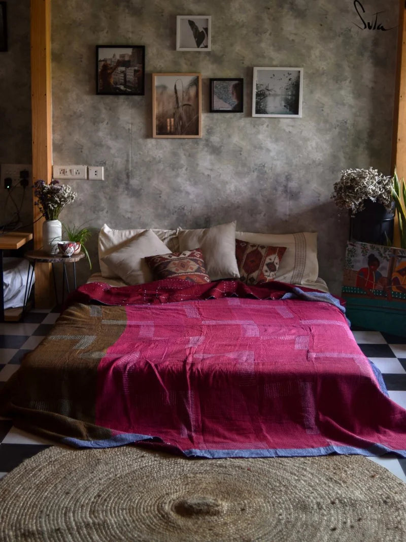 Bedroom with a bed covered in pink bedding, surrounded by framed pictures on the wall.