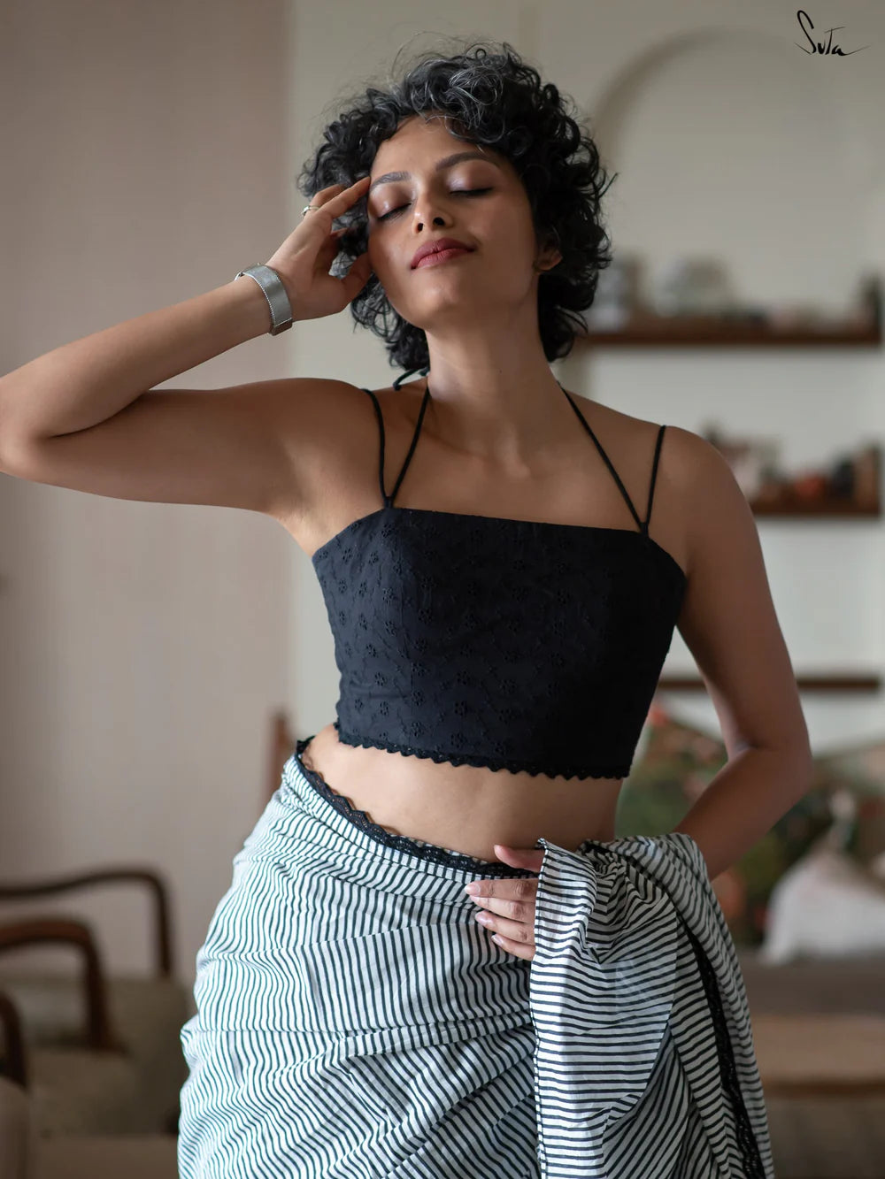 Woman wearing a black halter blouse and saree in an indoor setting