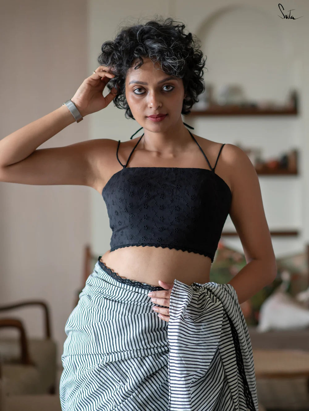 Woman wearing a black halter blouse and saree in an indoor setting